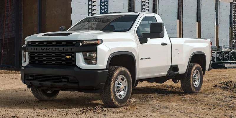 White Chevrolet Silverado 2500 HD pickup truck at a construction site.